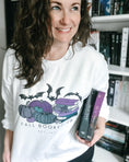 Load image into Gallery viewer, White Fall Booked Up sweatshirt with purple books by FireDrake Artistry™. Photo by @athousandbookishlives
