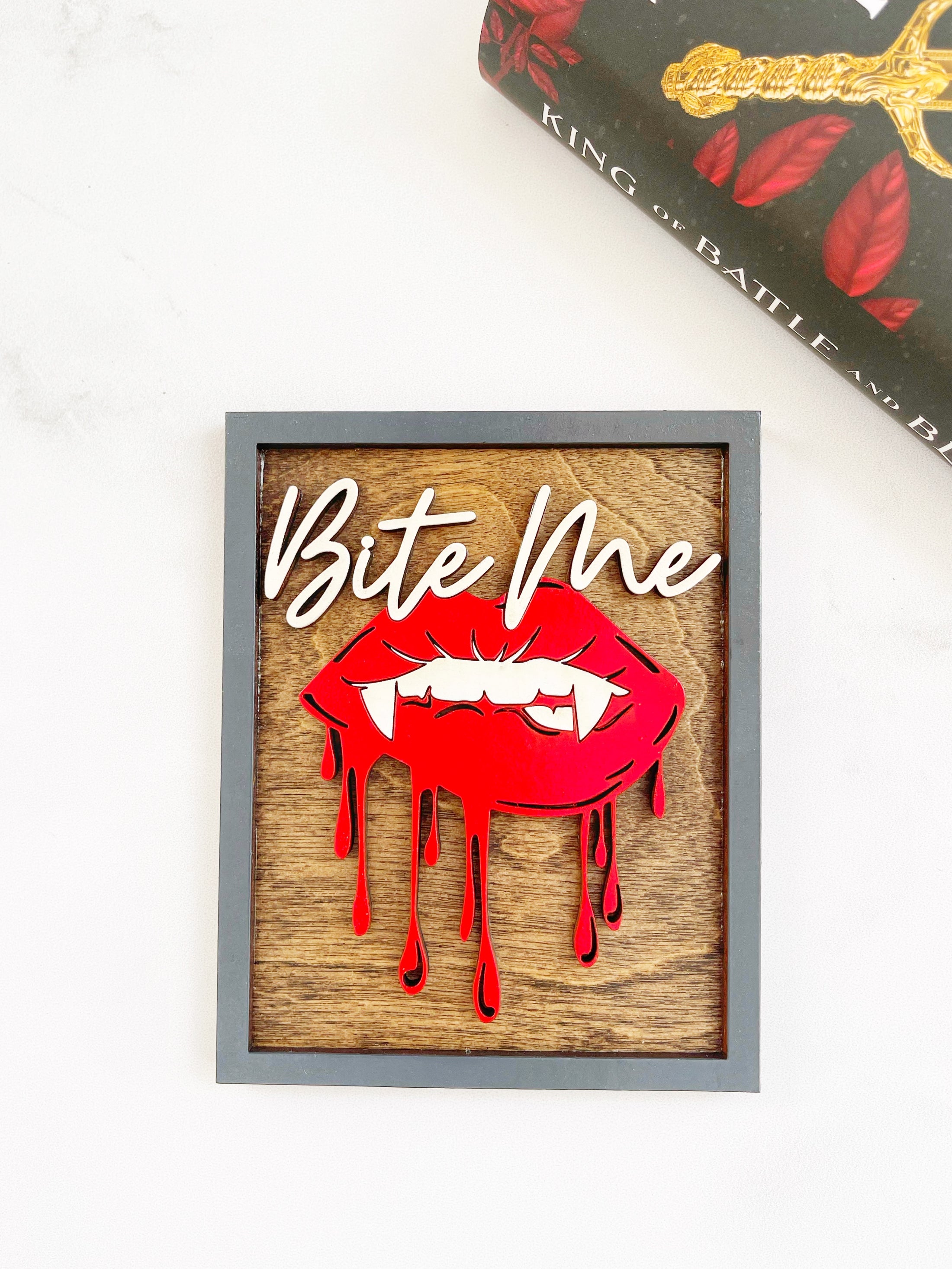 Bite Me Shelf Sign - FireDrake Artistry® wooden sign with natural background, dark grey frams, white "Bite Me" wording and red vampire lips.